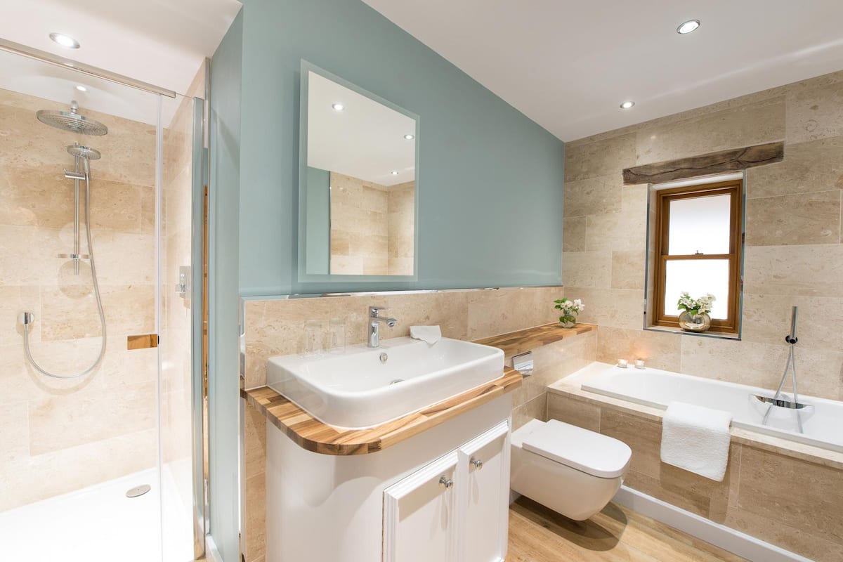 Un baño moderno con ducha envuelta en vidrio, dos lavamanos, una bañera y un inodoro.