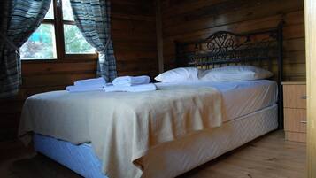 Une chambre dans une cabane en bois, avec un lit, des rideaux et une fenêtre.