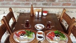 A wooden dining table with plates of food, bowls of condiments, and glasses of tea. - Agva Himalaya Motel (Sile)