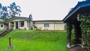 A residential property with a well-maintained lawn, a small garden feature, and a house with a covered porch. - Hillsborough Cottage Nuwara Eliya (Nuwara Eliya)