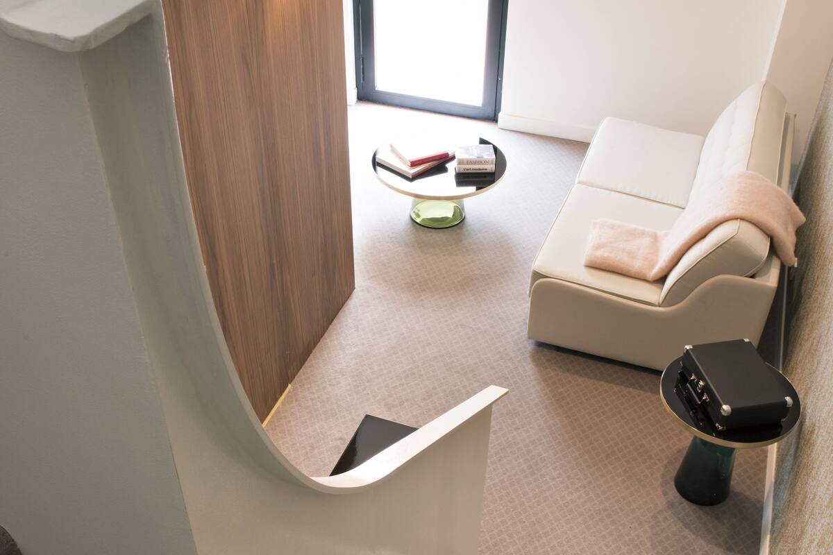 A modern interior with a staircase leading to a room, a sofa, and a small table with a book and a glass.