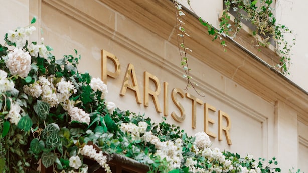 A building facade with the word "PARISTER" in large letters, surrounded by lush greenery and white flowers. - Hotel Parister & Spa (Paris)