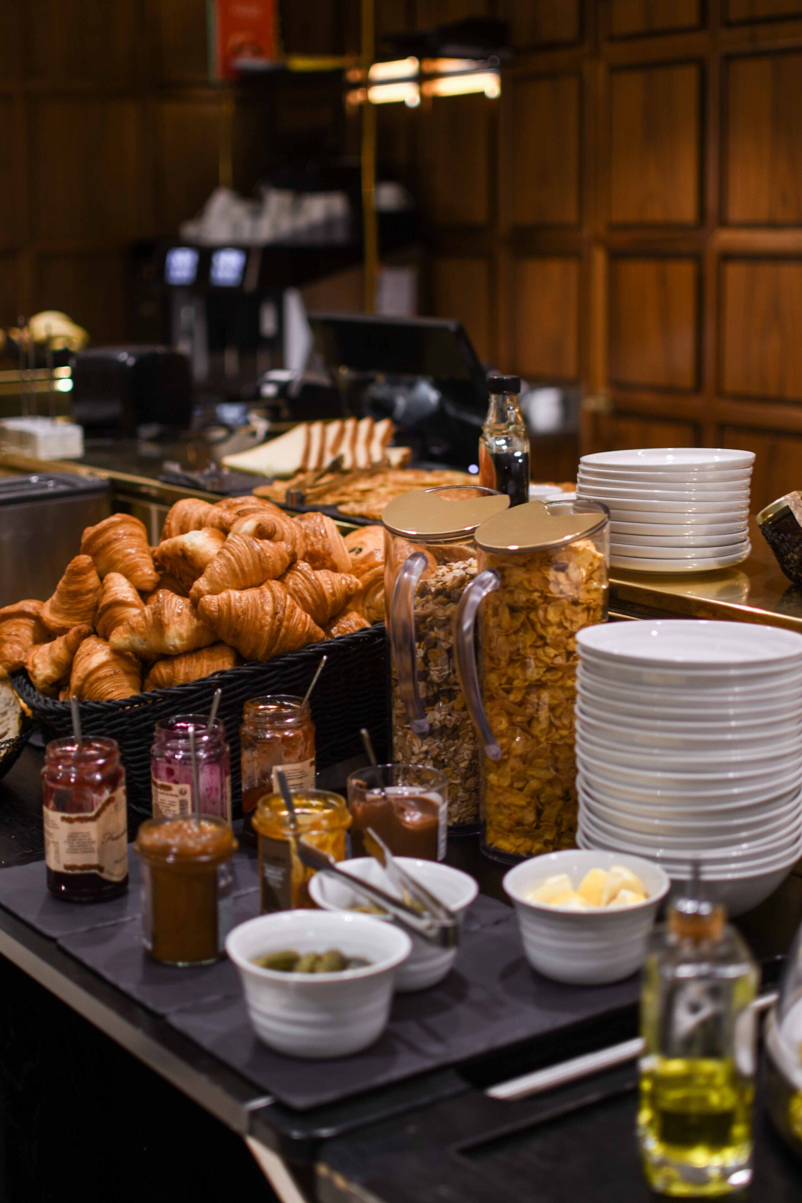 A buffet with croissants, jams, and various spreads.