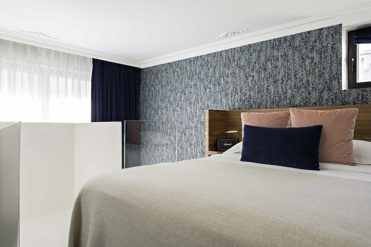 A hotel room with a bed, a nightstand, and a Marshall speaker.