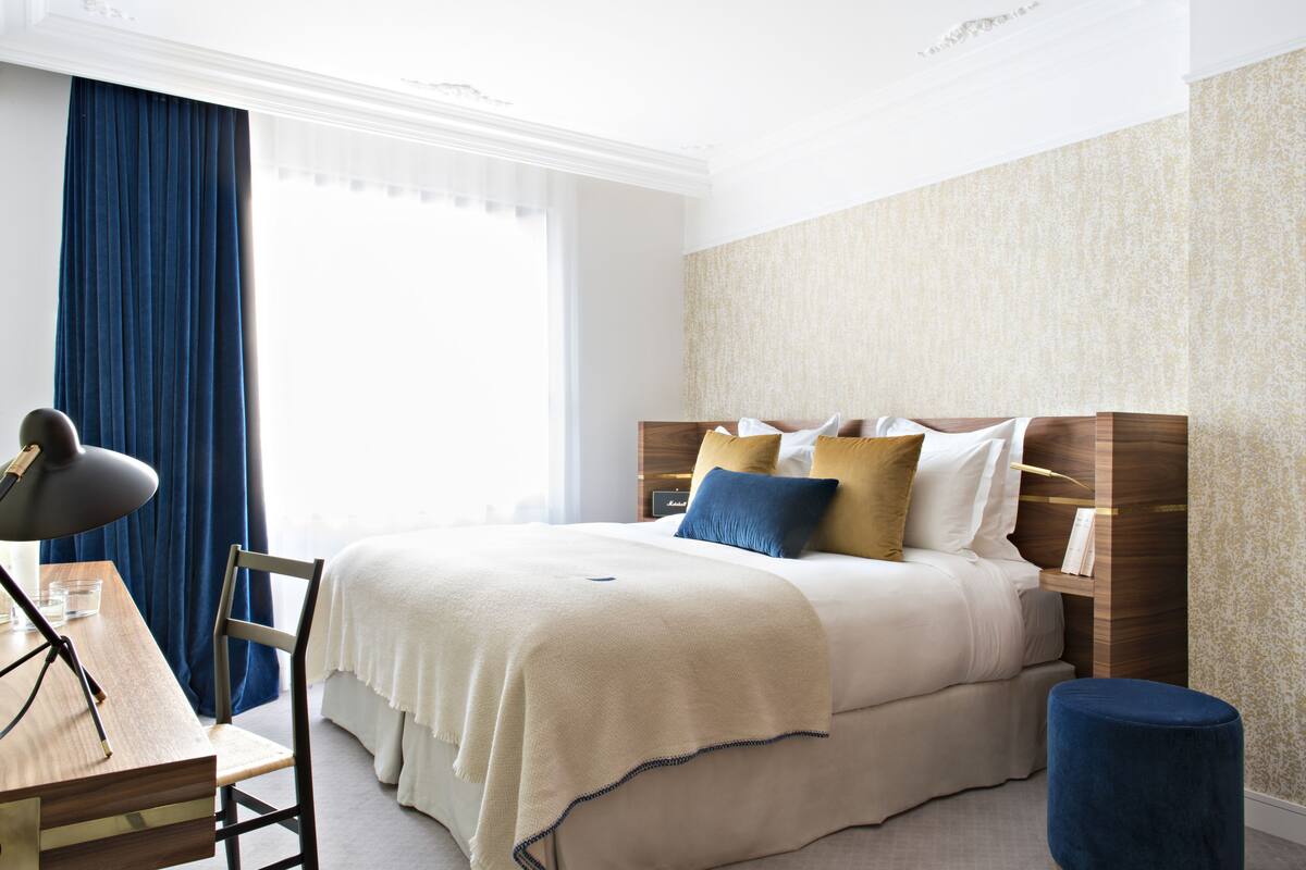 A neatly arranged bedroom with a bed, bedside table, lamp, and a chair.