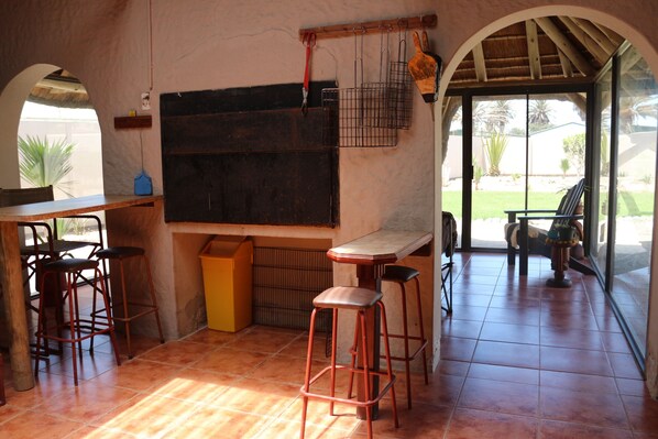 Una cocina con una pizarra grande, dos taburetes de bar, una mesa de madera y vistas al exterior a través de una puerta de vidrio.