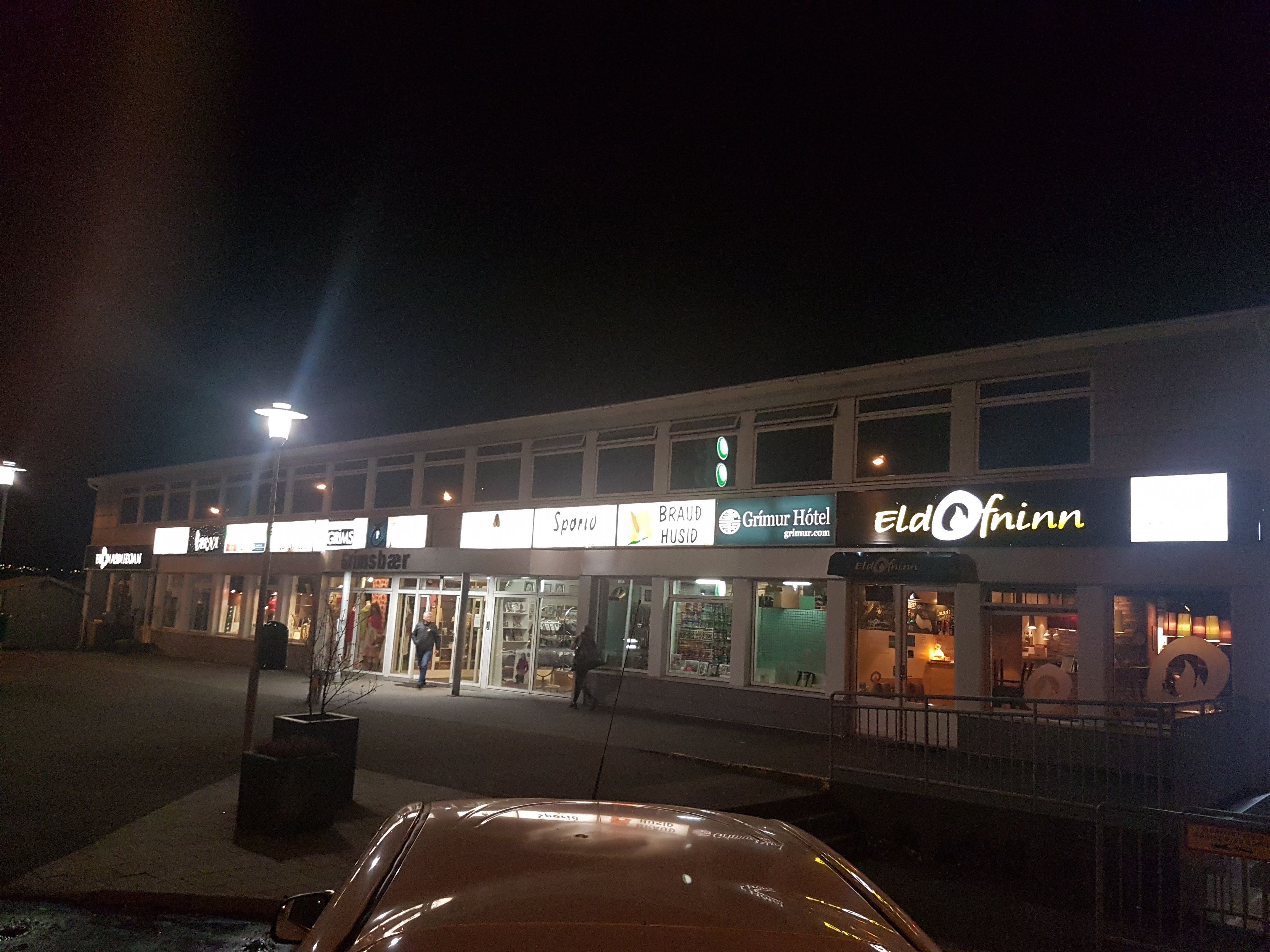 En bygning med flere butikker, herunder et hotel kaldet 'Grimur Hotel' og en butik ved navn 'Eldofinn'.