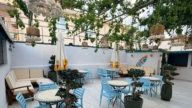 Un espace extérieur aménagé avec des tables et des chaises, des plantes en pot et des décorations suspendues.