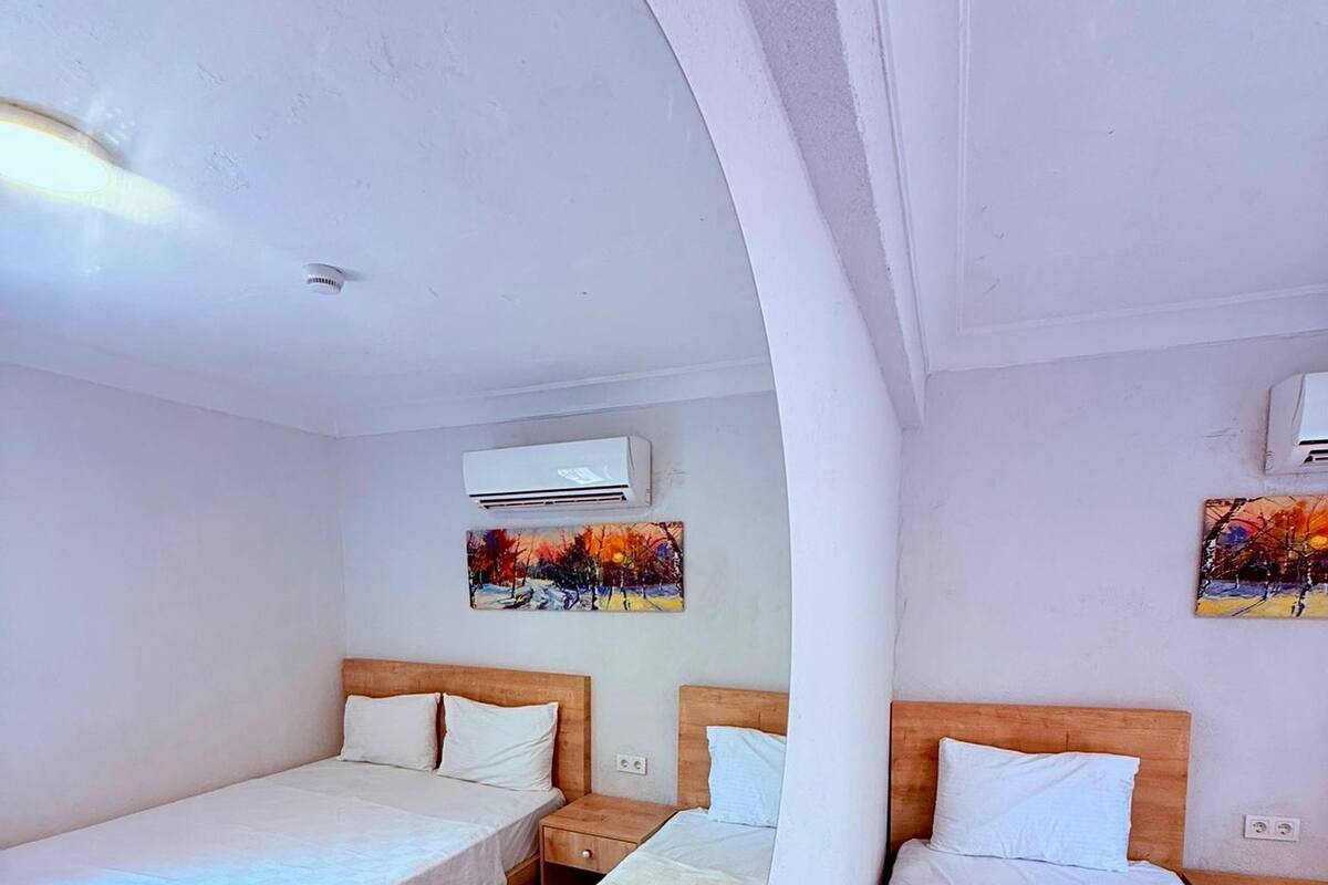 A room with two beds, a wooden headboard, a nightstand, and an air conditioning unit.
