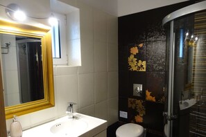 A bathroom with a white sink, a mirror with a gold frame, a toilet, and a shower area. - Artist's Villa Red Rose (Paxos)