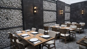 A restaurant with stone walls, wooden tables, and chairs.