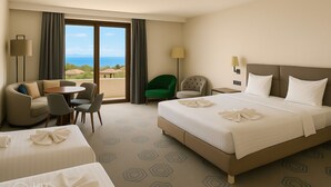 Habitación de hotel con una cama grande, dos sillones, una mesita y vista al mar.