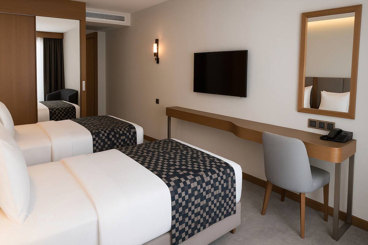 A hotel room with two beds, a desk, a chair, a television, and a mirror.