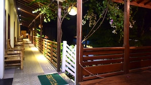 A covered walkway with wooden benches and a green mat with 'WELCOME' written on it. - Panda Cottage - Hostel (Gili Trawangan)