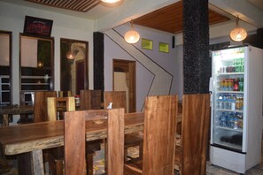 A restaurant interior with wooden furniture and a white refrigerator. - Panda Cottage - Hostel (Gili Trawangan)