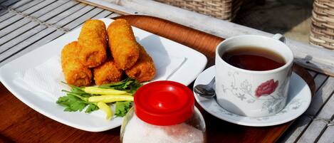 A tray with fried food, a cup of tea, and a salt shaker.