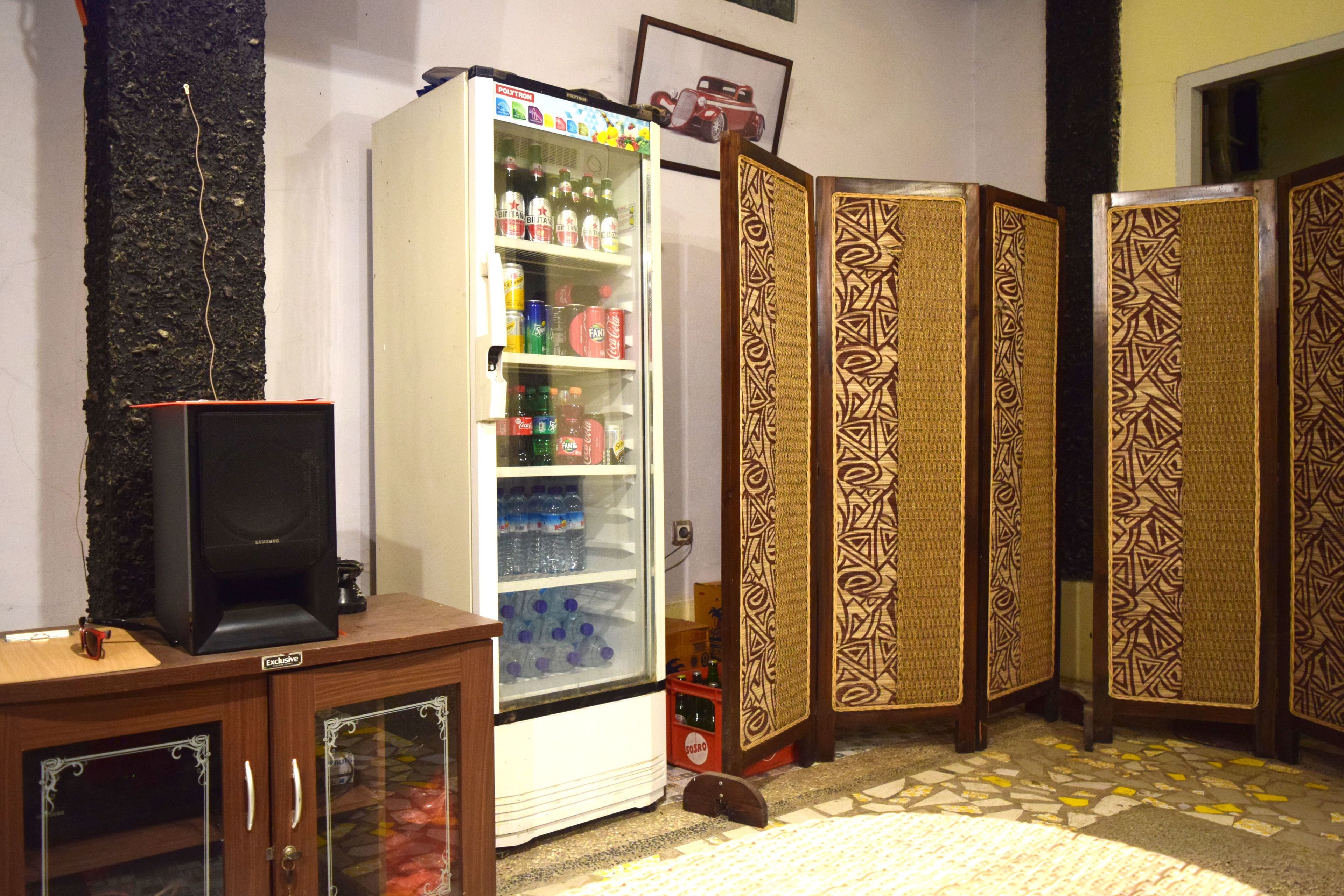 Een kamer met een koelkast vol drankjes, een televisie op een kast en een kamerdoorkijk met een patroon.