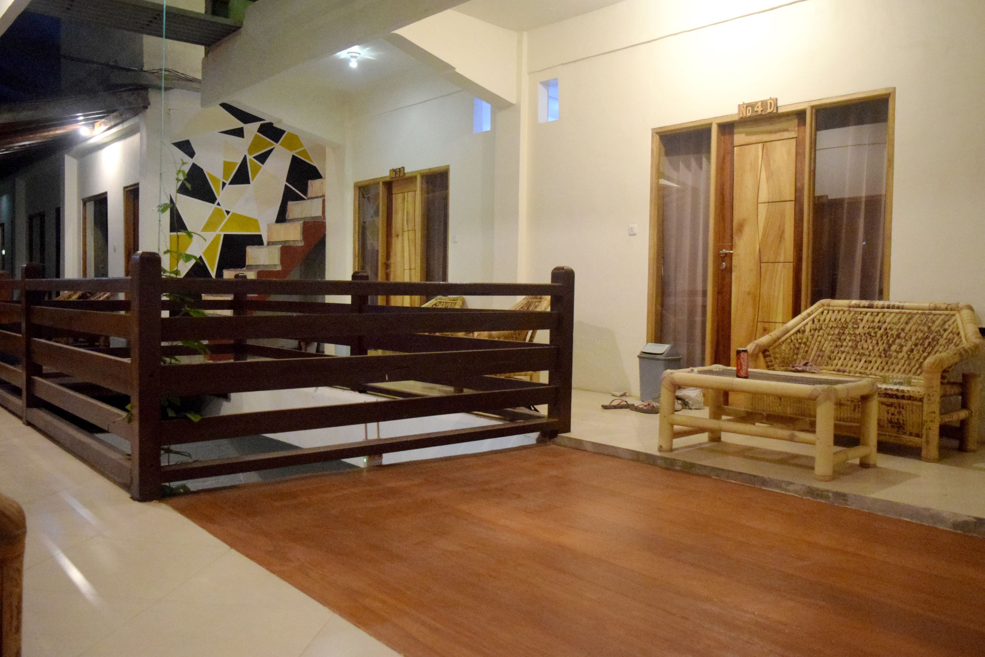 Una habitación con una cama de madera, un sofá y una mesita. Hay puertas y una ventana con cortinas.