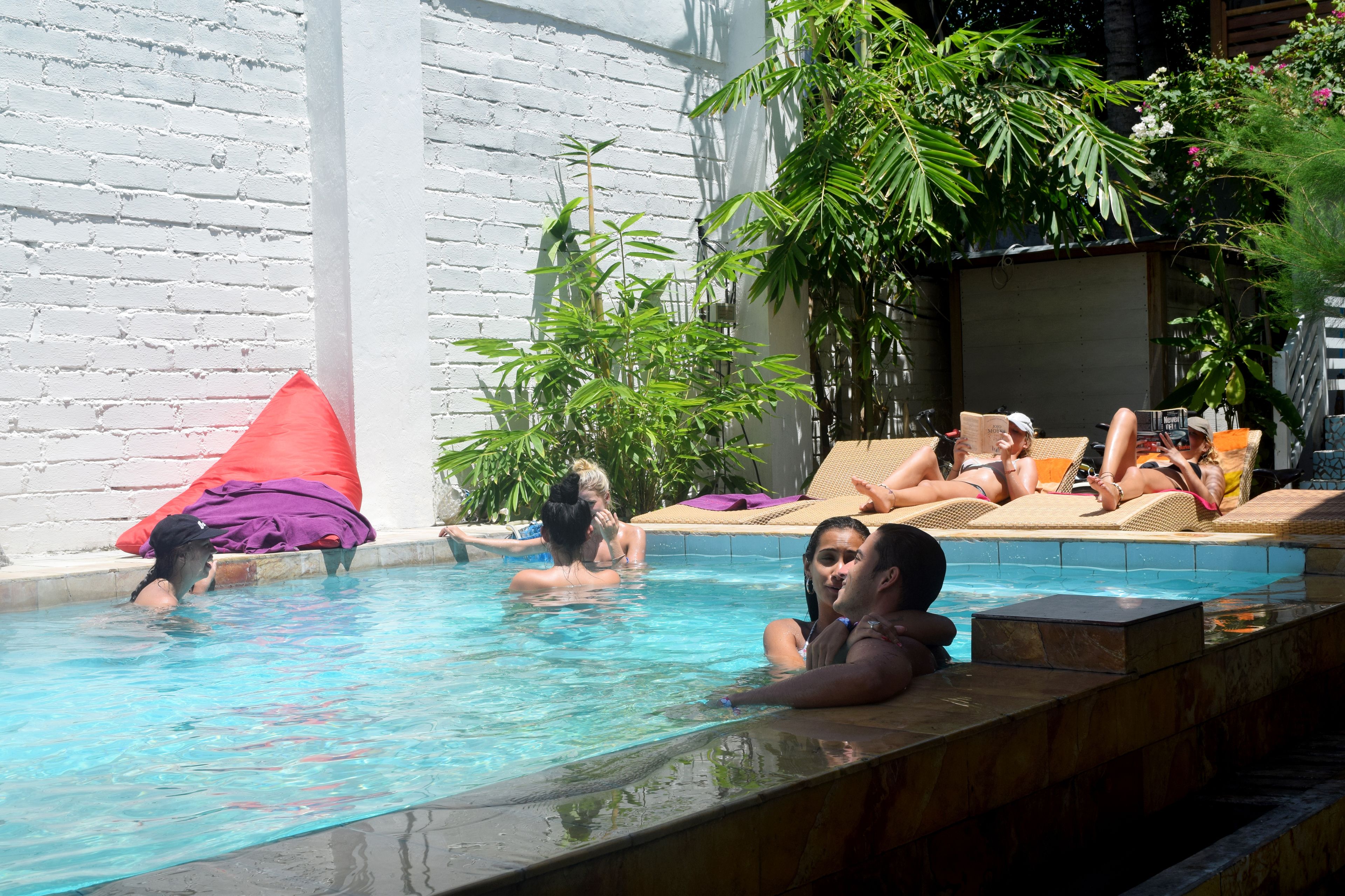 A swimming pool with lounge chairs and a white brick wall.