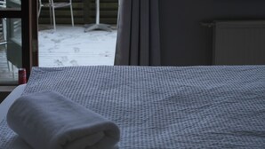 Una habitación con cama, ventana y vista a un paisaje nevado.