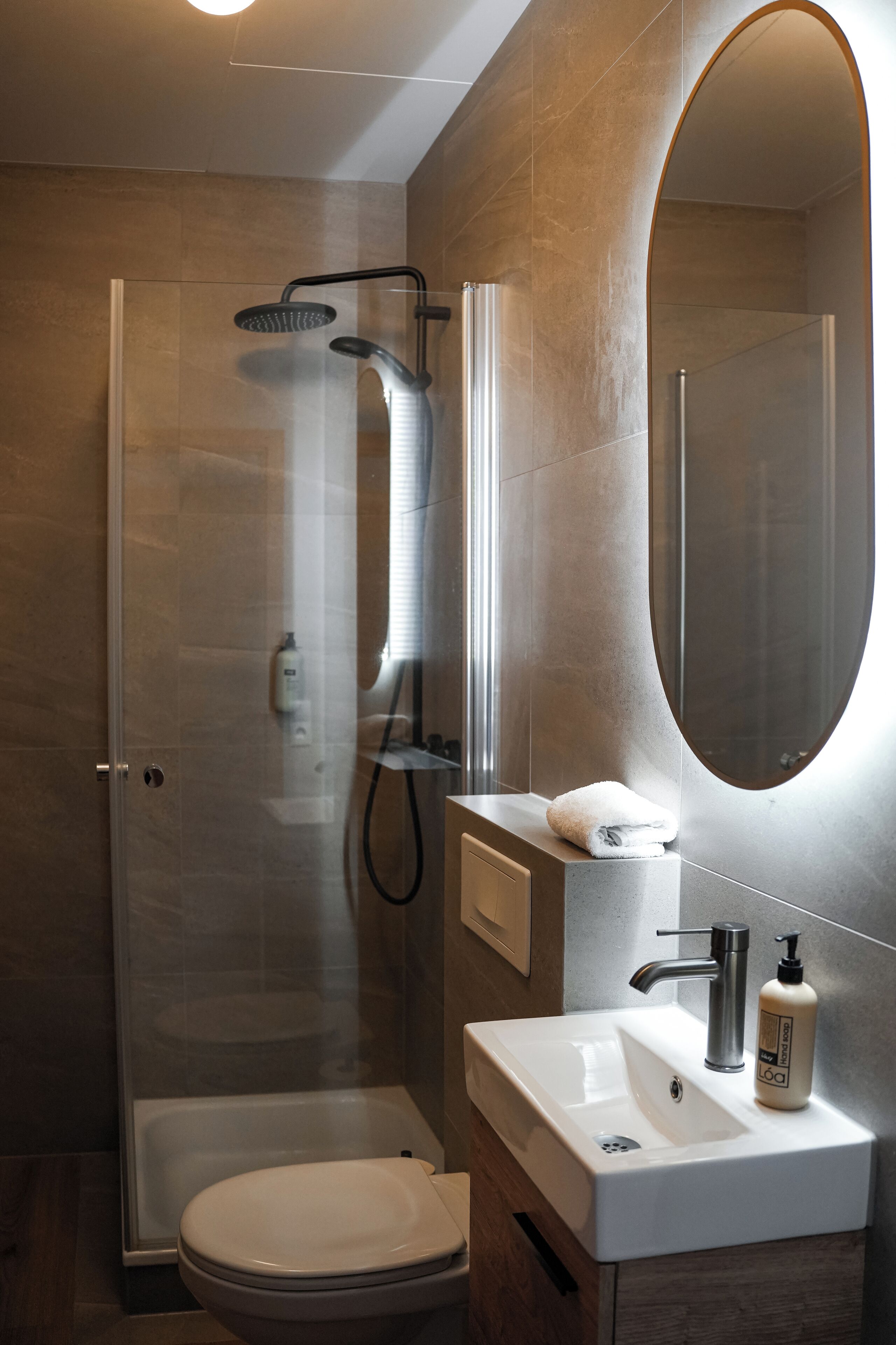 Een moderne badkamer met een douchecabine van glas, een witte wastafel en een grote spiegel.