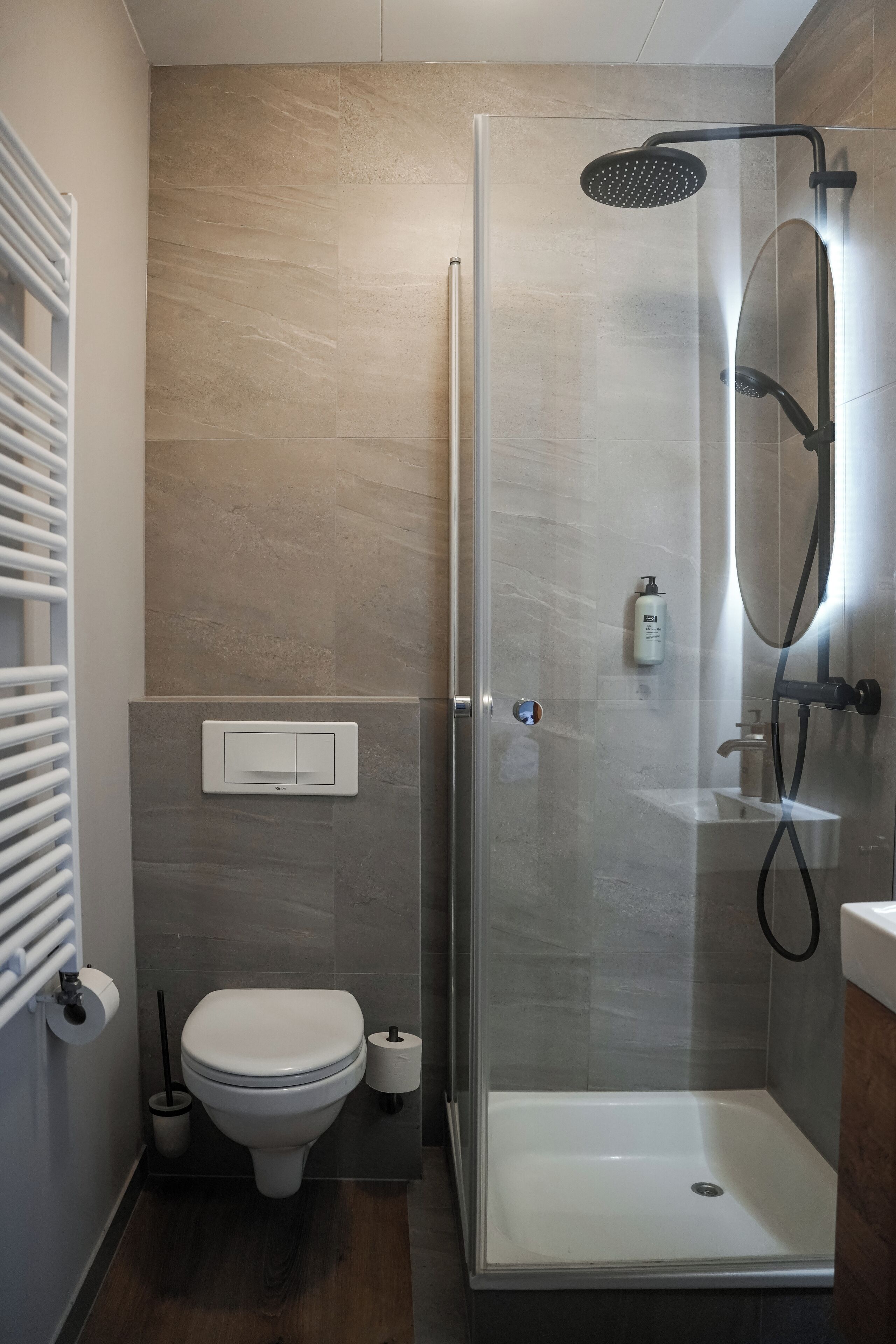 A modern bathroom with a glass-enclosed shower, a toilet, and a sink.