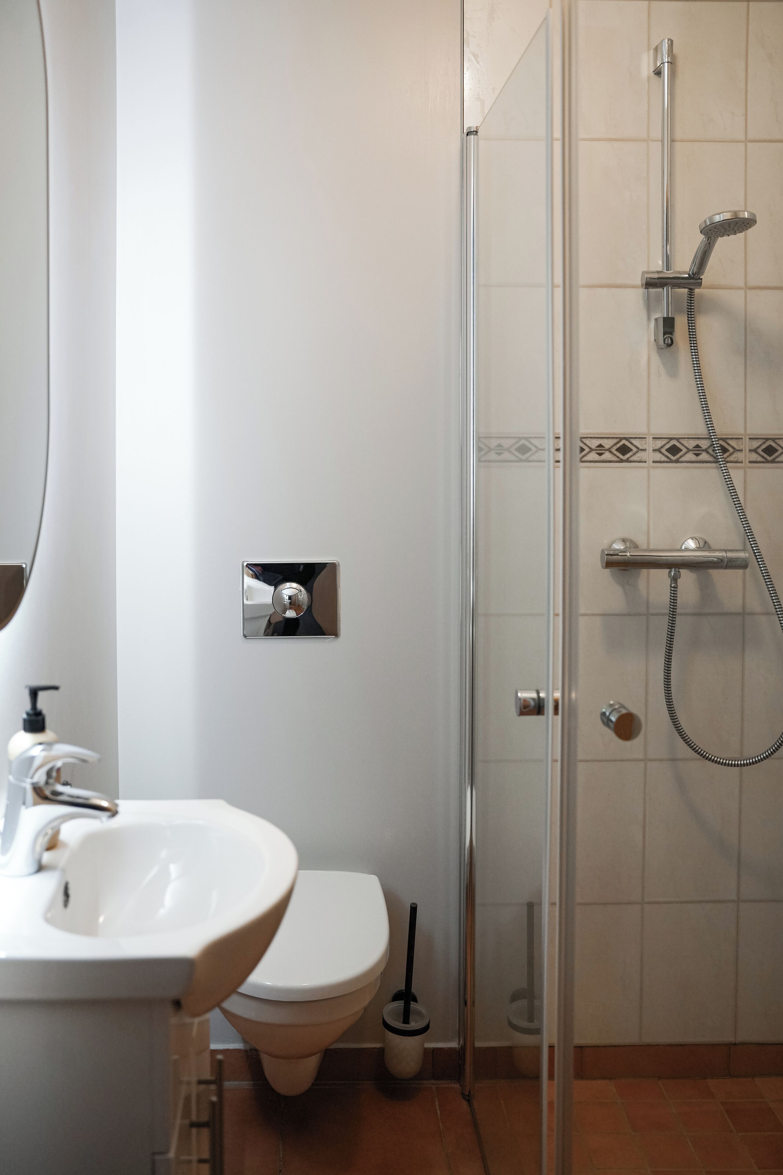 A bathroom with a glass-enclosed shower, a white sink, and a toilet.