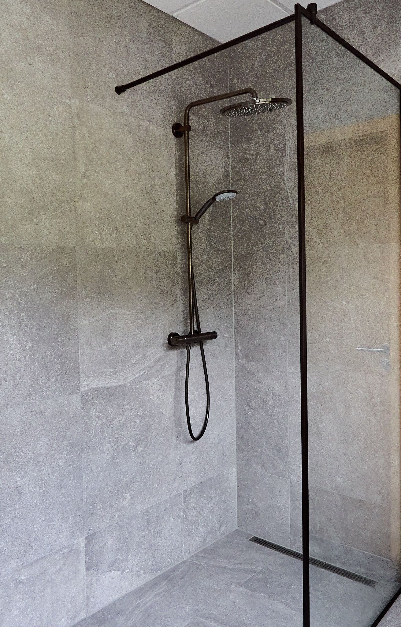 Un box de ducha moderno con puerta de cristal y estructura metálica.