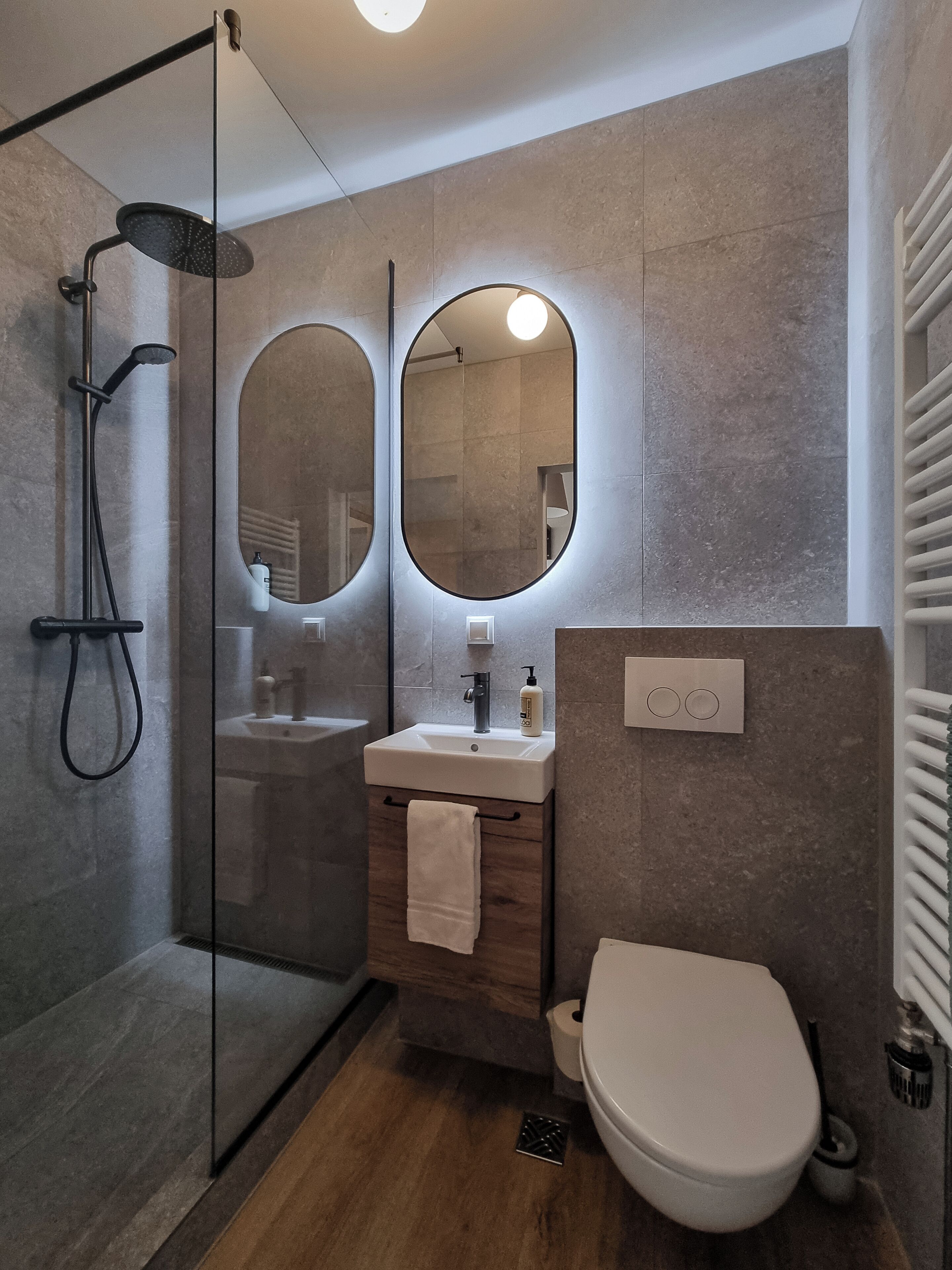 A modern bathroom with a glass-enclosed shower, a sink with a mirror, and a toilet.