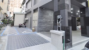 Un edificio moderno con entrada cubierta, una moto estacionada afuera y un espacio de estacionamiento para discapacitados de color azul.