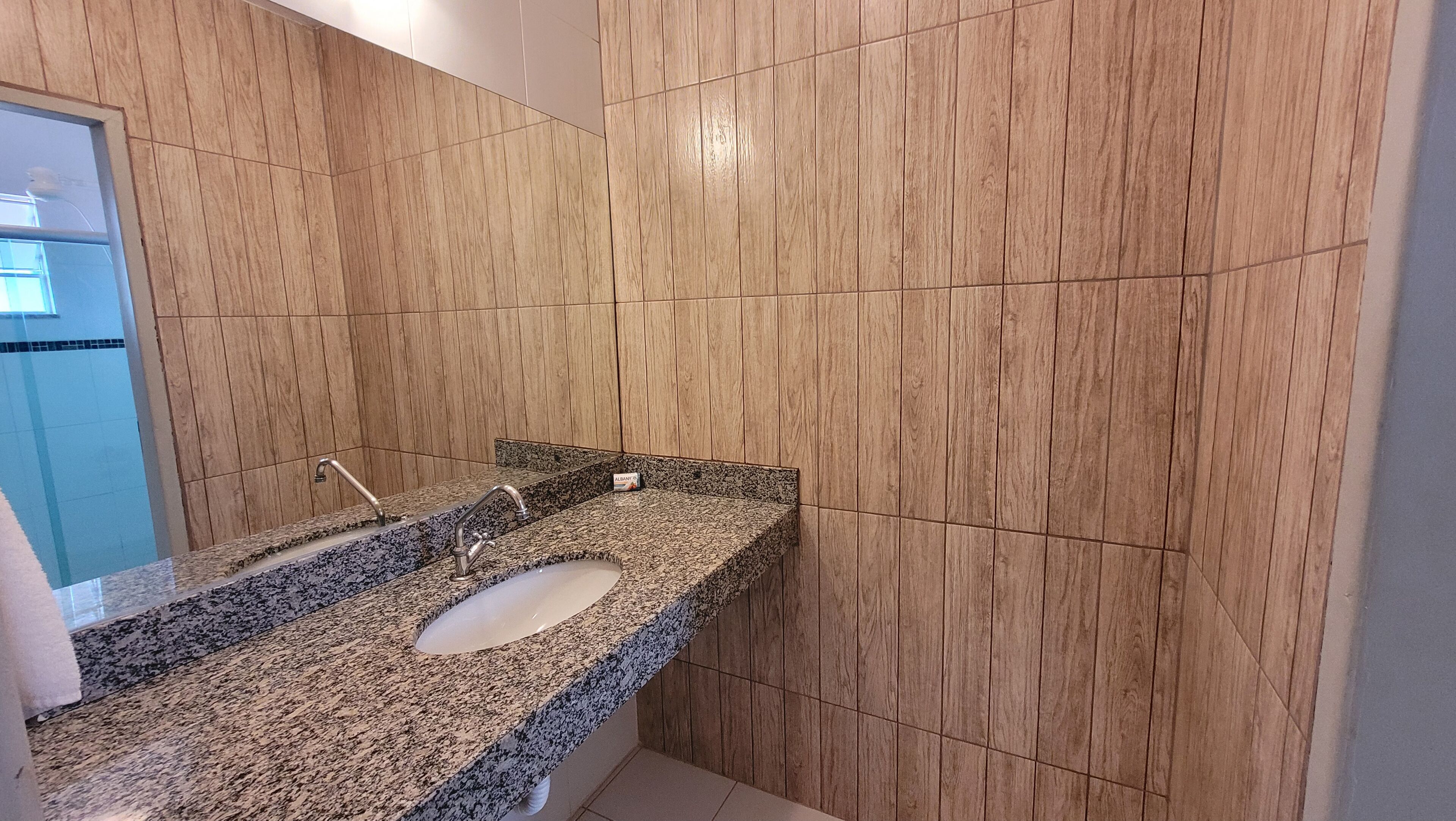 A bathroom with a granite countertop, a sink, and wooden paneling on the walls.