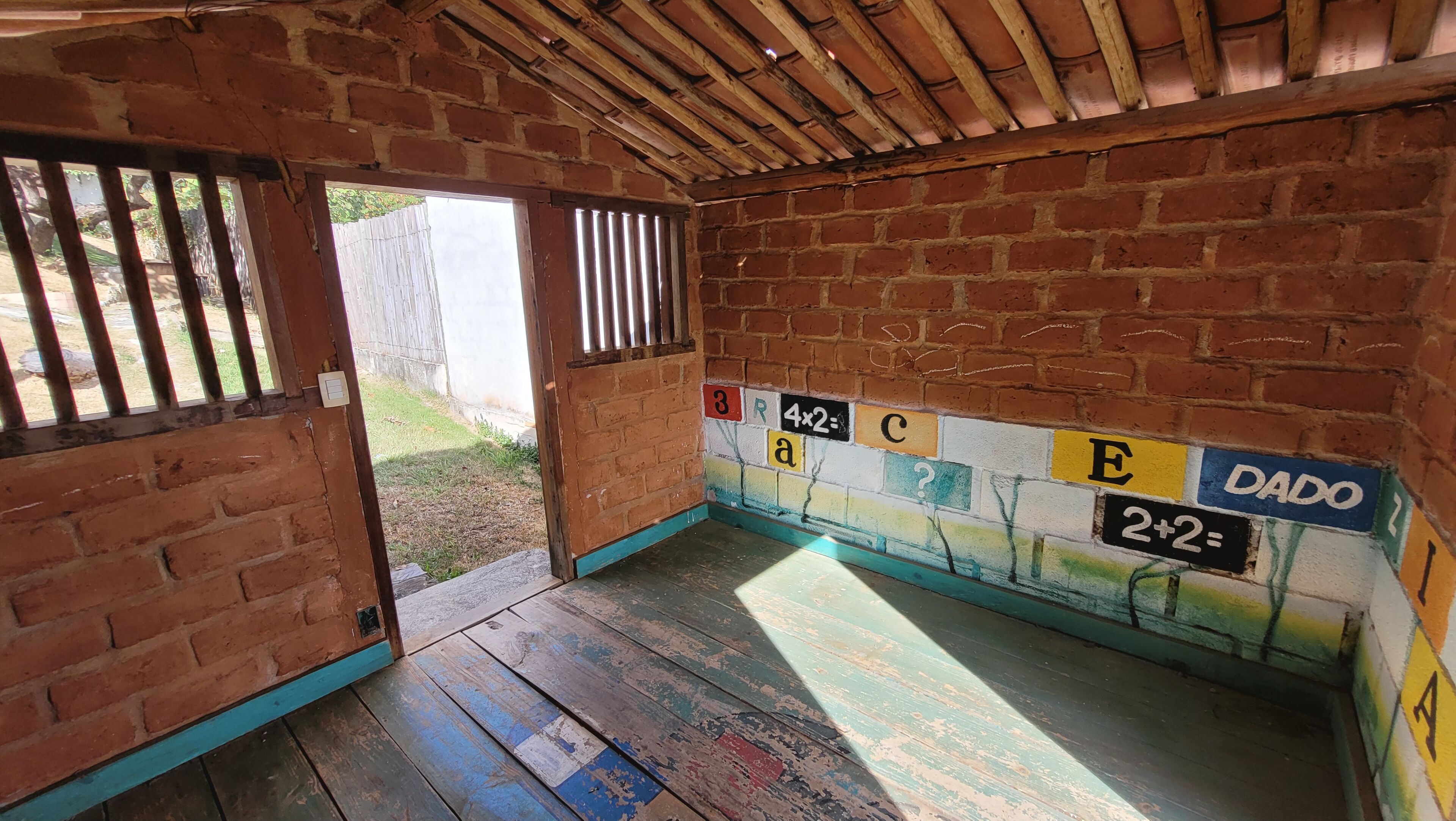Una habitación rústica con techo de madera y paredes de ladrillo, que presenta un mural llamativo con números y letras.