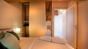 A bedroom with a bed, a bedside table, a wardrobe, and a door leading to another room. - Verona For Rent La Colombina (Verona)
