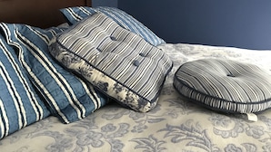 A bed with blue and white striped pillows and a floral-patterned bedspread. - The Destination B&B (Salem)