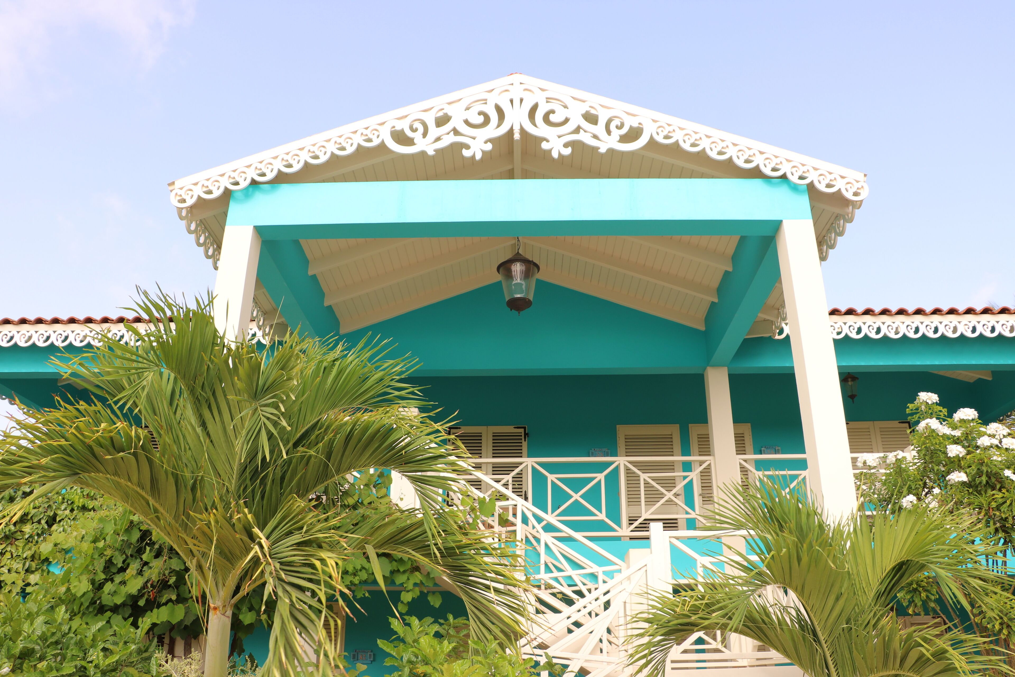A turquoise building with a white balcony and a lantern.