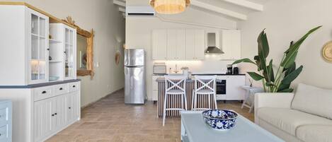 Una cocina moderna con armarios blancos, un refrigerador de acero inoxidable y una lámpara colgante.