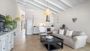 A modern kitchen with white cabinets, a black countertop, and a hanging light fixture. - Caribbean Lofts Bonaire (Kralendijk)