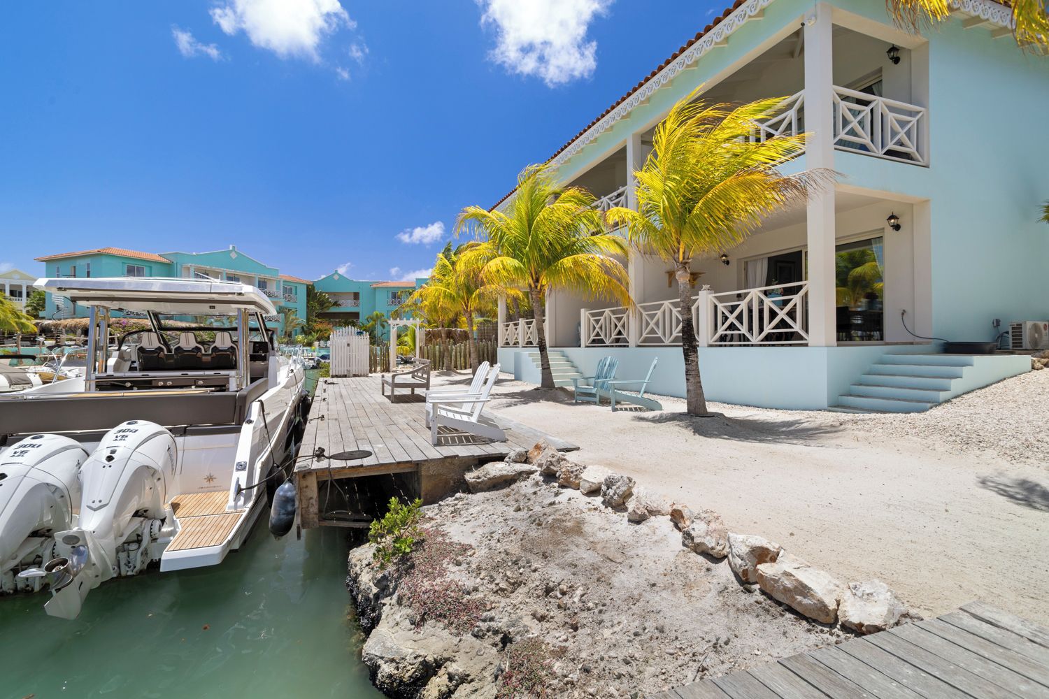 A beachfront property with a dock, lounge chairs, and a building with a balcony.