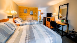 A hotel room with two beds, a desk, a chair, a TV, and a mirror.