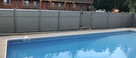 A swimming pool with a wooden building in the background.
