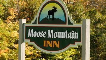 Letrero del Moose Mountain Inn con una silueta de alce y un paisaje de montaña.