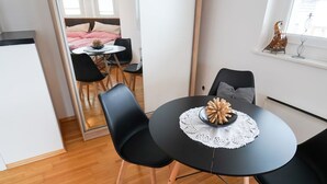A modern dining area with a round table, black chairs, and a wooden floor. - Schlafgut Küssler Zell am See (Zell am See)