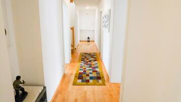 A narrow hallway with wooden flooring and white walls.