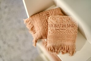 A beige knitted throw with a textured pattern and fringe edges, placed on a white surface.