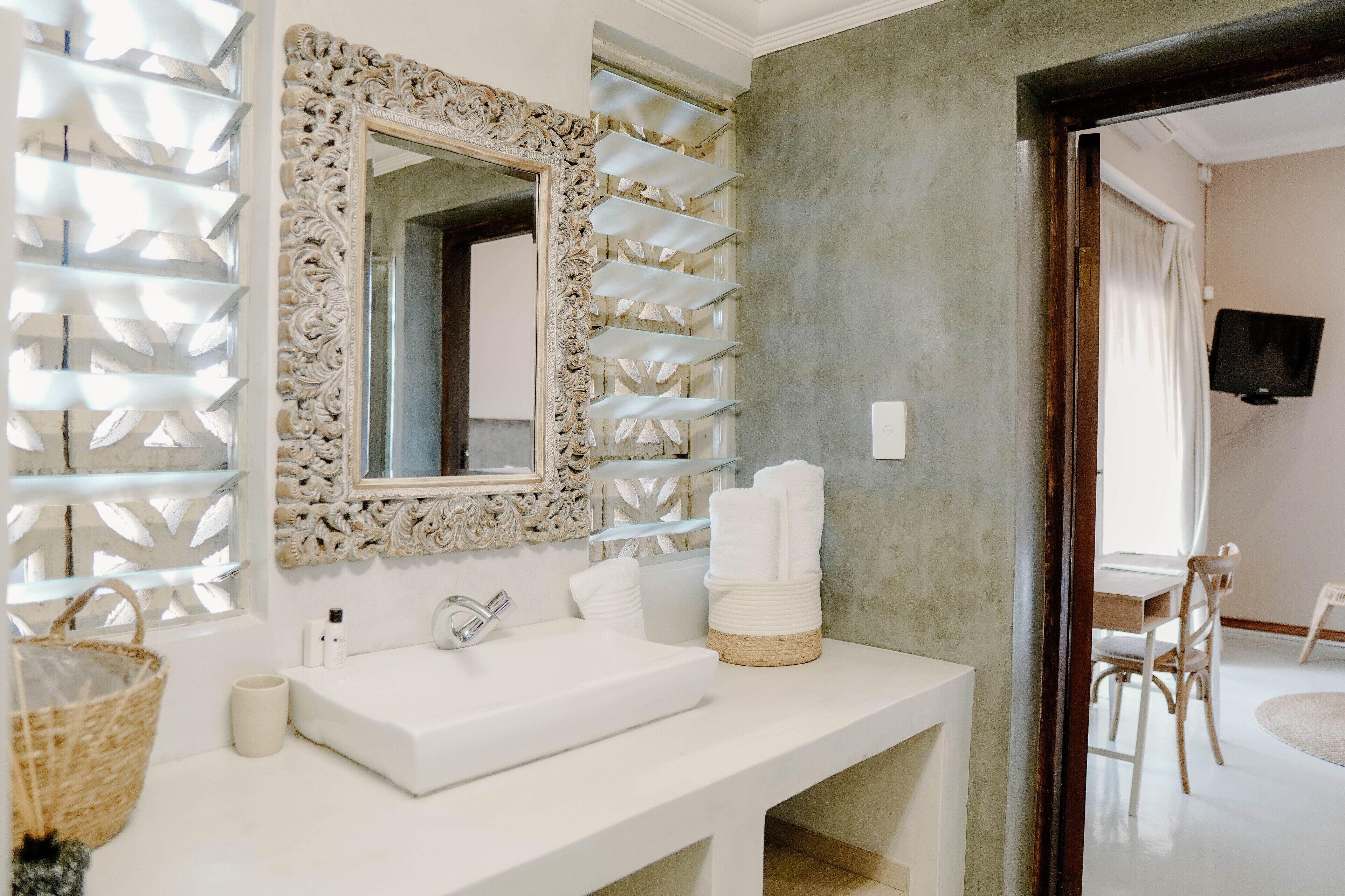Une salle de bain avec un lavabo blanc, un miroir et un panneau décoratif mural.