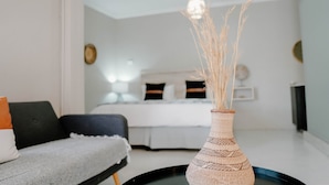 A modern bedroom with a bed, a bedside table, and a vase with dried plants. - Lighthouse Guesthouse & Cafe (Groblersdal)