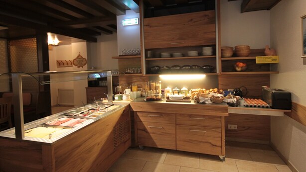 A kitchen with wooden cabinets, a breakfast bar, and various food items.