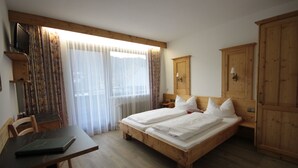 A room with a wooden bed, a desk, and a wardrobe.