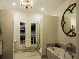 Un baño moderno con una bañera de mármol, una cabina de ducha de vidrio y un espejo grande.