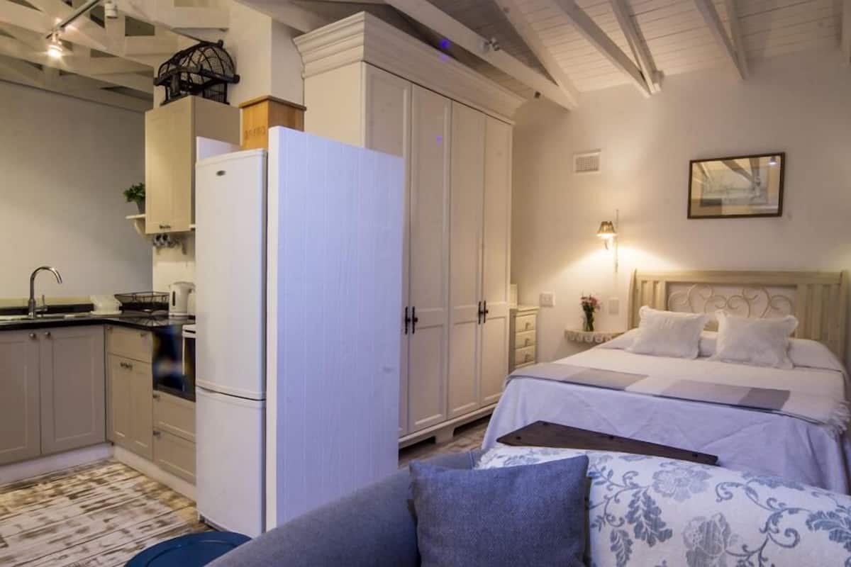A bedroom with a bed, bedside table, and a nightstand with a lamp.